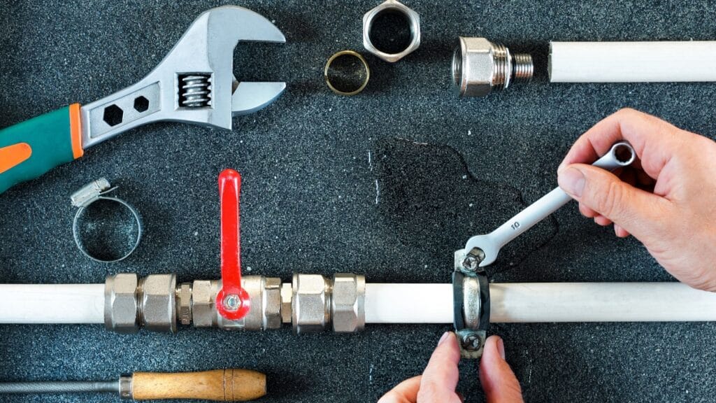Plumber repairing a pipe valve with an adjustable wrench in Upland