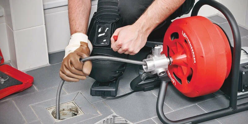 Plumber using a drain-cleaning machine in Upland