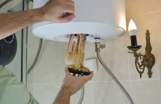 Technician removing mineral buildup from a water heater in Upland