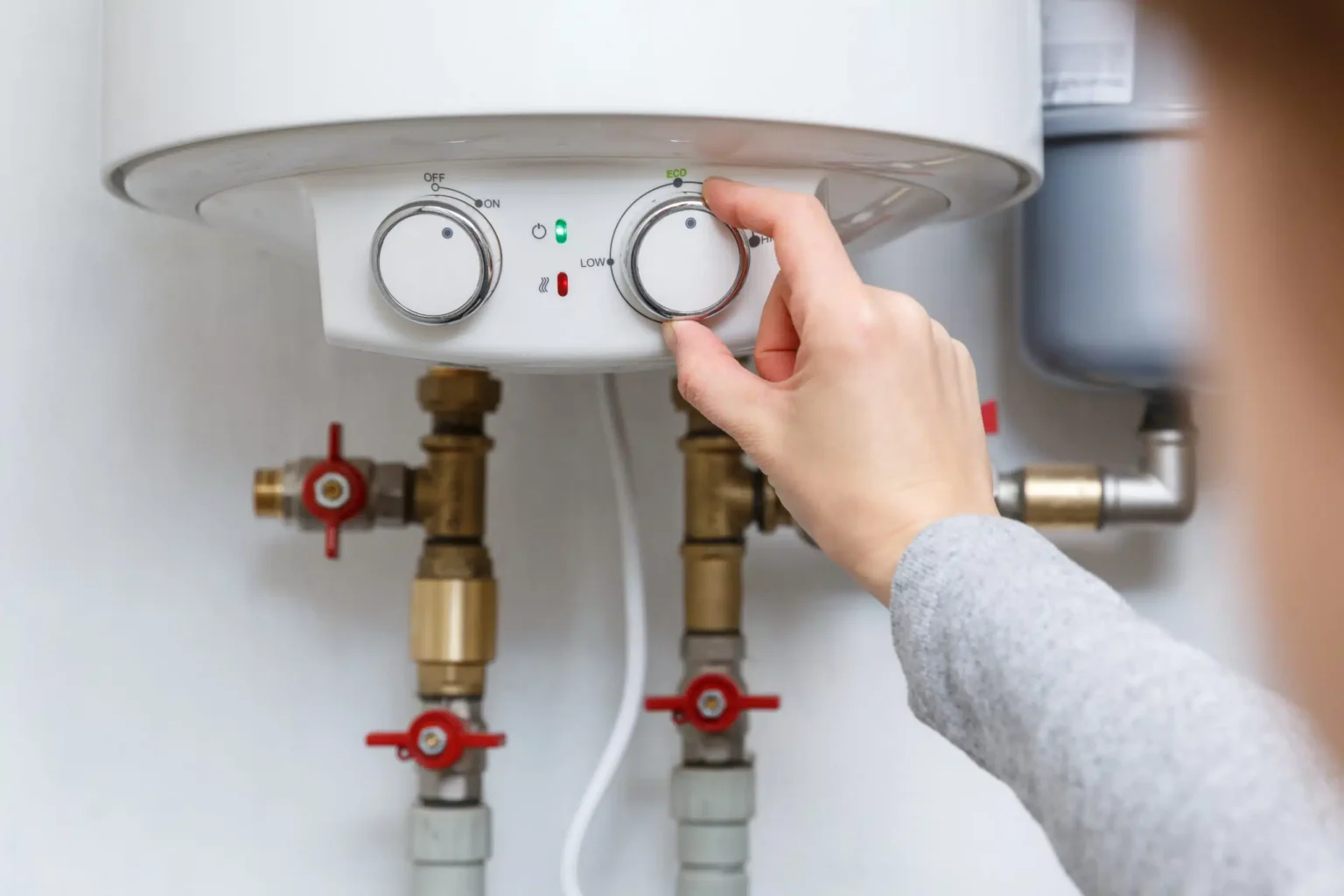 Homeowner adjusting the temperature controls on a water heater in Upland